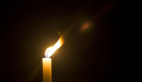 Close-up of lit candle in darkroom