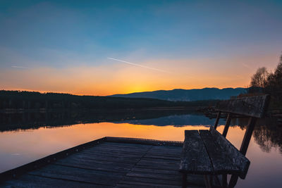 Pier over lake against sky during sunset