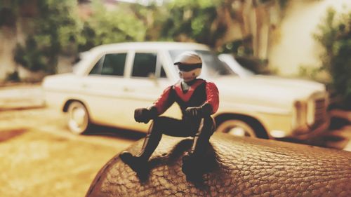 Man wearing sunglasses sitting on car in city