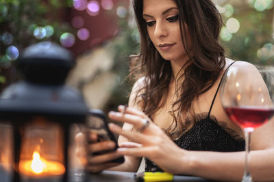 Beautiful woman using mobile phone at table