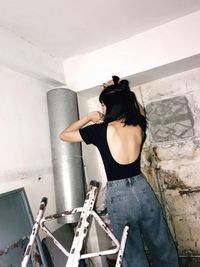 Rear view of woman standing against wall