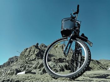 Low angle view of bicycle wheel against clear blue sky