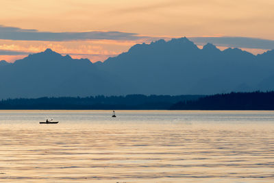 Scenic view of lake and silhouette mountains against sky