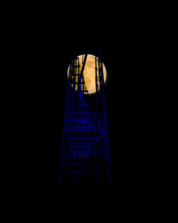 Low angle view of illuminated tower against dark sky