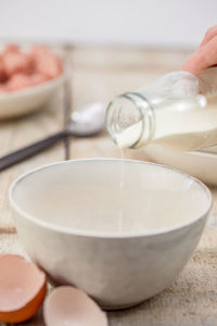 Cropped image of hand pouring milk in bowl