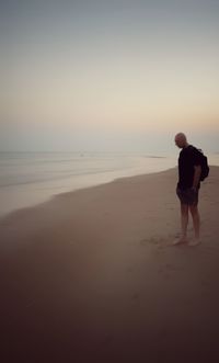 Rear view of man standing on beach against sky