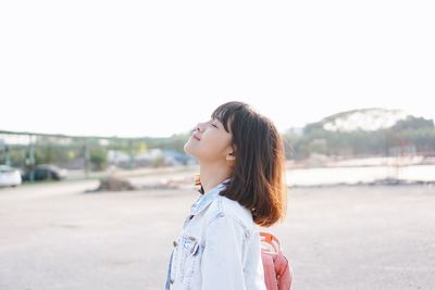 Young woman looking away against clear sky