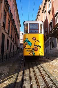 Railroad tracks by street in city against sky