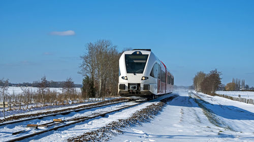 Train on snow covered railroad tracks against sky