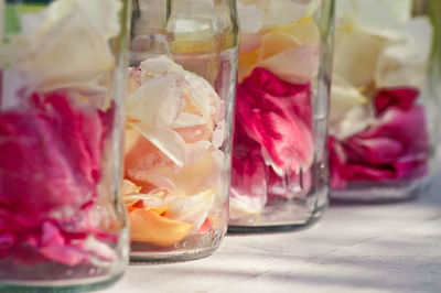 Rose petals in glass jars on table at yard