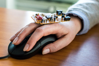 Close-up of hand wearing circuit board while using computer on table