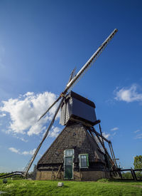 Low angle view of traditional windmill on field against sky