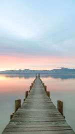 Pier over lake against sky during sunset