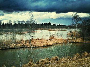 Calm lake against cloudy sky