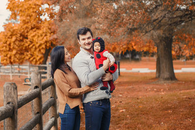 Portrait of father carrying cute daughter while standing with woman in park