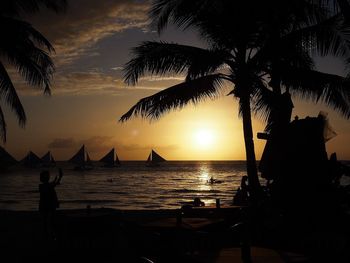 Silhouette palm trees on beach against sky during sunset