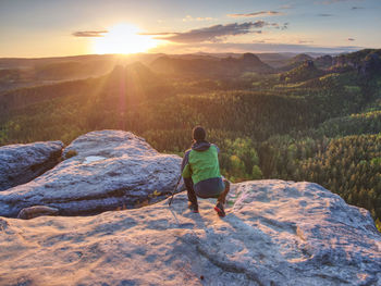 Rear view of man looking at mountains against sky during sunset