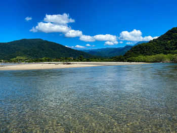 Scenic view of sea and mountains against blue sky