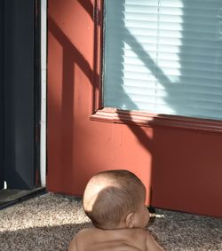 Portrait of boy by window on wall