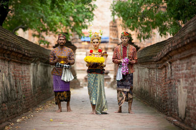 Portrait of people in traditional clothing standing outside at temple