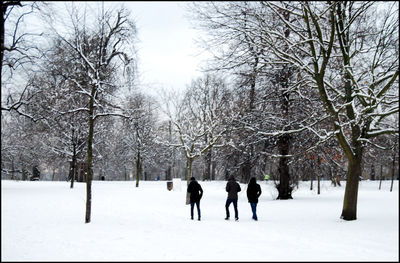 People on snow covered landscape against sky