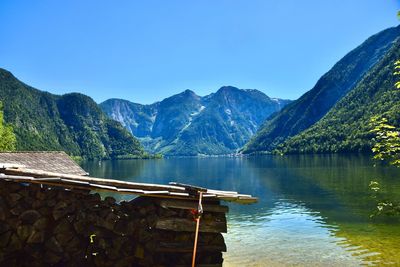 Scenic view with boathouse, lake and mountains against clear blue sky