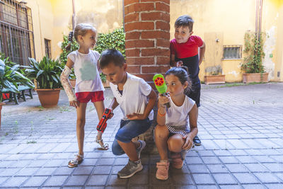 Group of little boys of different ages having fun and playing together in a courtyard