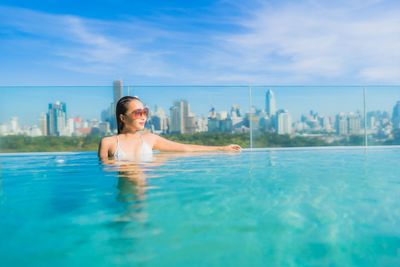 Portrait of smiling man swimming in pool against sky