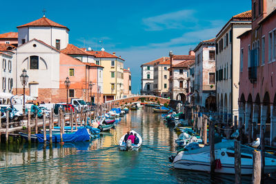 People on boat in canal amidst buildings in city