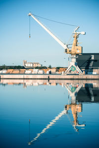 Cranes at commercial dock against blue sky