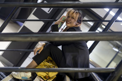 Portrait of businesswoman sitting on steps at railroad station