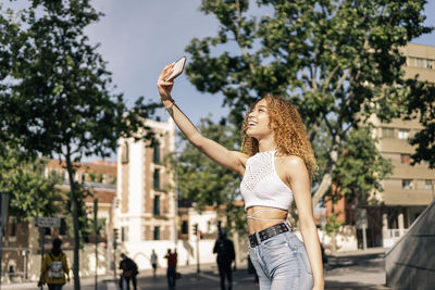 Young woman holding umbrella in city