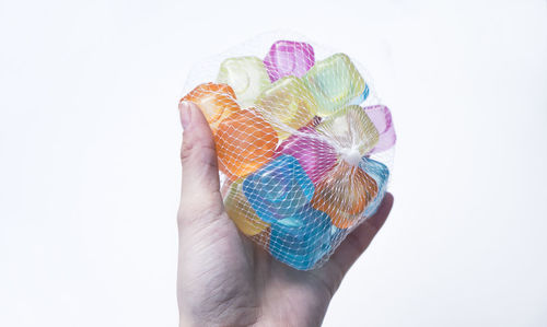 Midsection of person holding multi colored pencils against white background