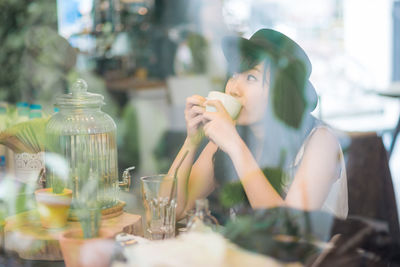 Women drinking coffee looking away while sitting at restaurant
