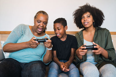 Family playing video game while sitting on sofa at home