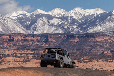 Full frame full length view of a jeep on rugged terrain with snow capped mountains in the background