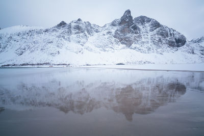 Scenic view of lake by snowcapped mountain against sky