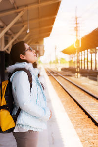 Side view of man looking away at railroad station