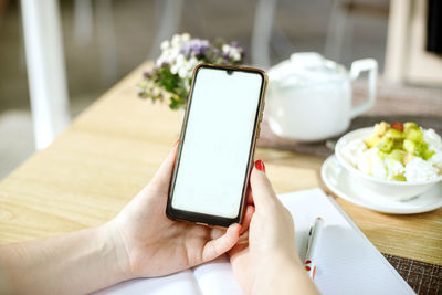 Midsection of person using mobile phone on table