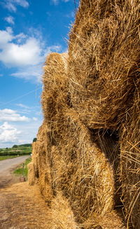 Close-up of hay bales on field against sky