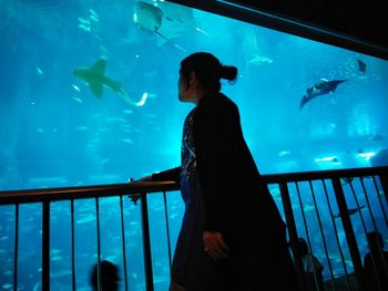 Rear view of woman standing in aquarium