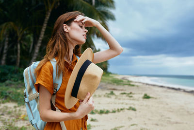 Young woman standing at beach against sky