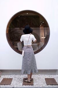 Portrait of young woman standing against wall