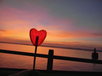 Close-up of heart shape on beach against sunset sky