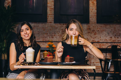 Portrait of a smiling young woman with drink in restaurant