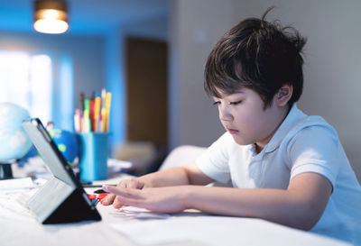 Boy looking away while sitting on table