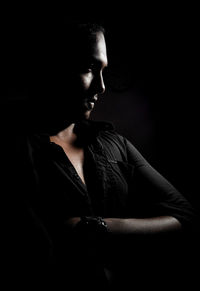 Portrait of young woman looking away over black background