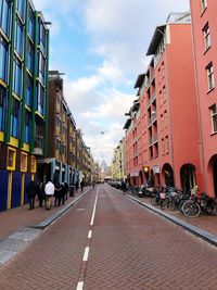 People walking on road amidst buildings in city against sky