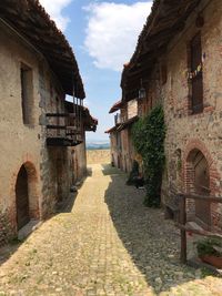 Footpath amidst old buildings against sky