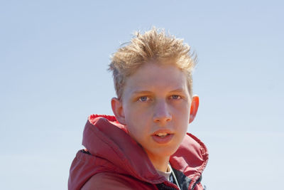 Portrait of teenage boy against clear sky on sunny day